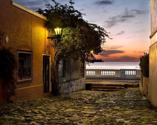Calle empedrada con farol que baja hacia el río al anochecer