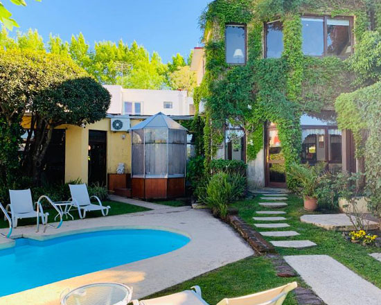 Jardín con piscina, reposeras y muros cubiertos de enredaderas