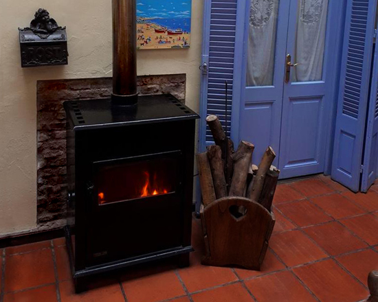 Estufa a leña encendida junto a una puerta celeste
