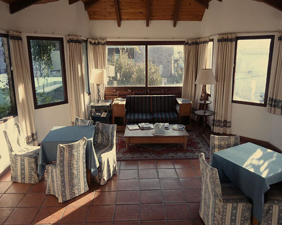 Sala de estar con sillones y ventanales hacia el jardín